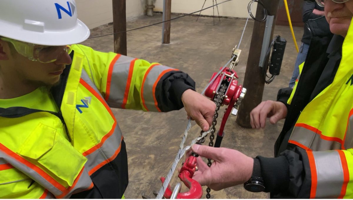 How to Become an Aerial Lineman: Skills and Training Tips Aerial lineman student learning how to hang steel strand cable in an indoor training facility.