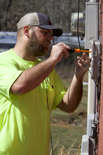 A fiber installation technician hooks up a home with fiber cable. Conquer Digital Divide A fiber installation technician hooks up a home with fiber cable. Conquer Digital Divide