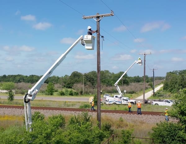 Fiber Optic Boom: Transformative Trends Lighting Up the Future National OnDemand aerial lineman preparing to hang fiber across a railroad track.